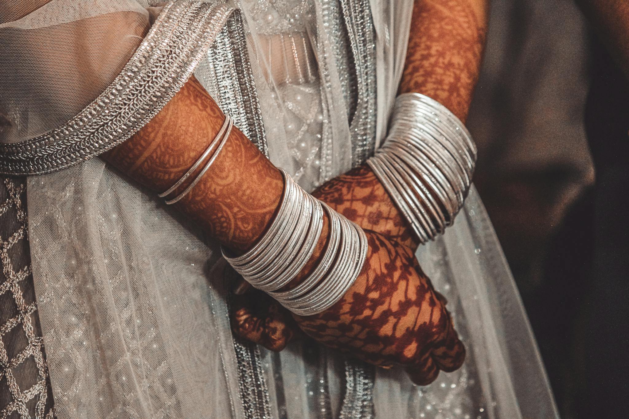 Detailed close-up of traditional bridal henna and silver bangles in India.